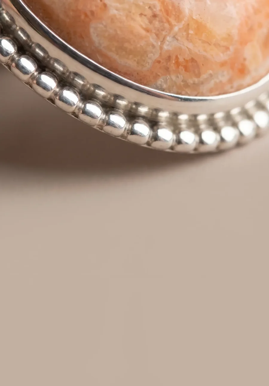 Close on a fossilized coral cabochon and its beaded silver bezel